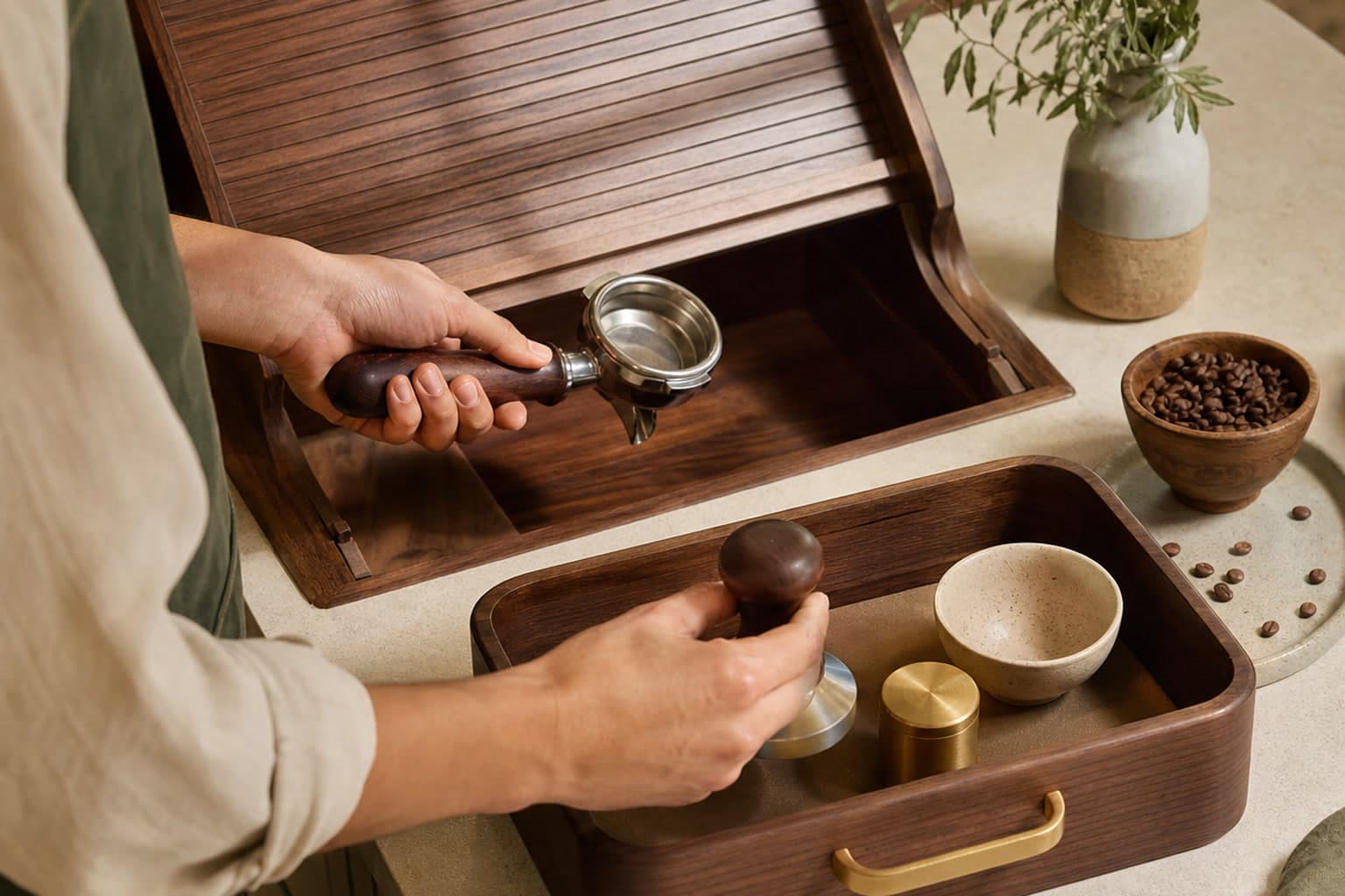A barista moves a portafilter and tamper from an open roll-top wooden bay into a caddy with a cup and brass weight.